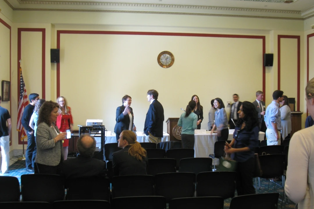 A group of people standing around and having conversations in a room.