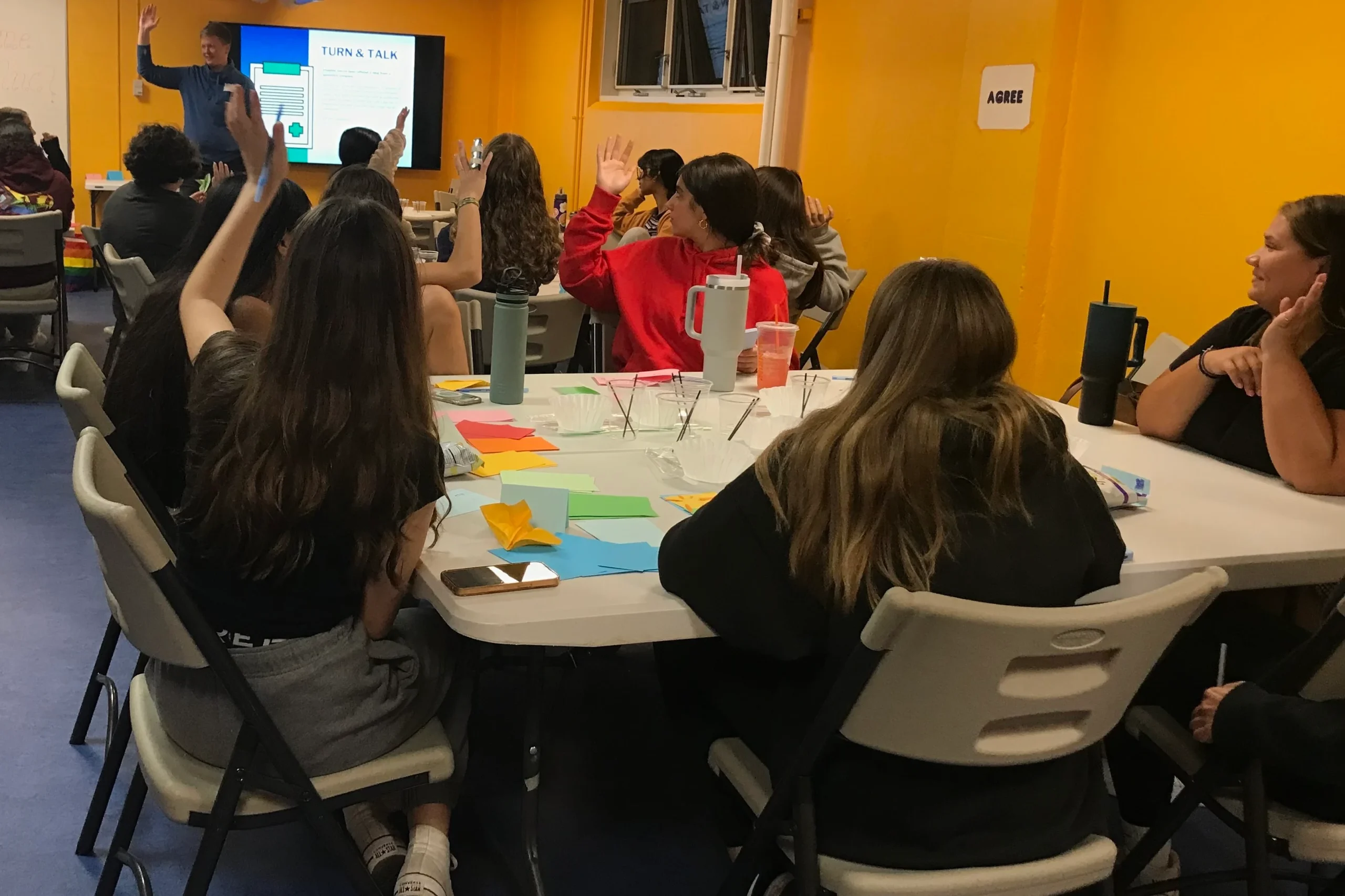 Students raise their hands to participate in an interactive workshop.