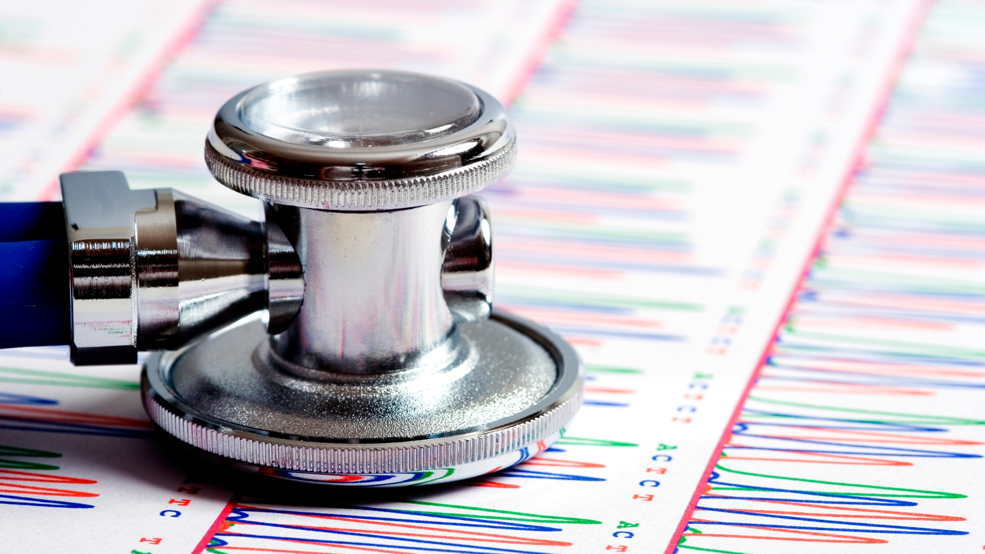 A stethoscope sits atop a paper displaying genetic code.
