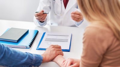 A doctor talking to a couple while sitting at a table.