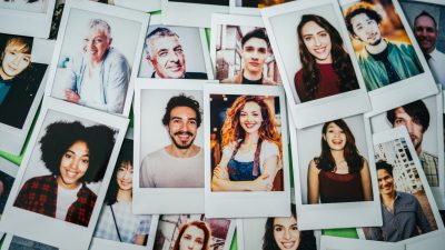 Many photos of people arranged on a table.