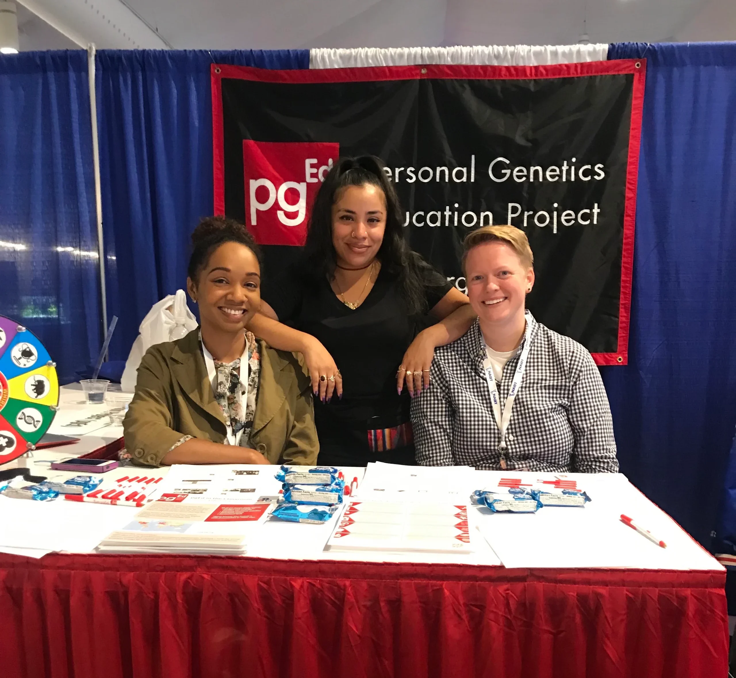 Robin, Vika, and Florcy are posing at the PGED exhibitor booth.